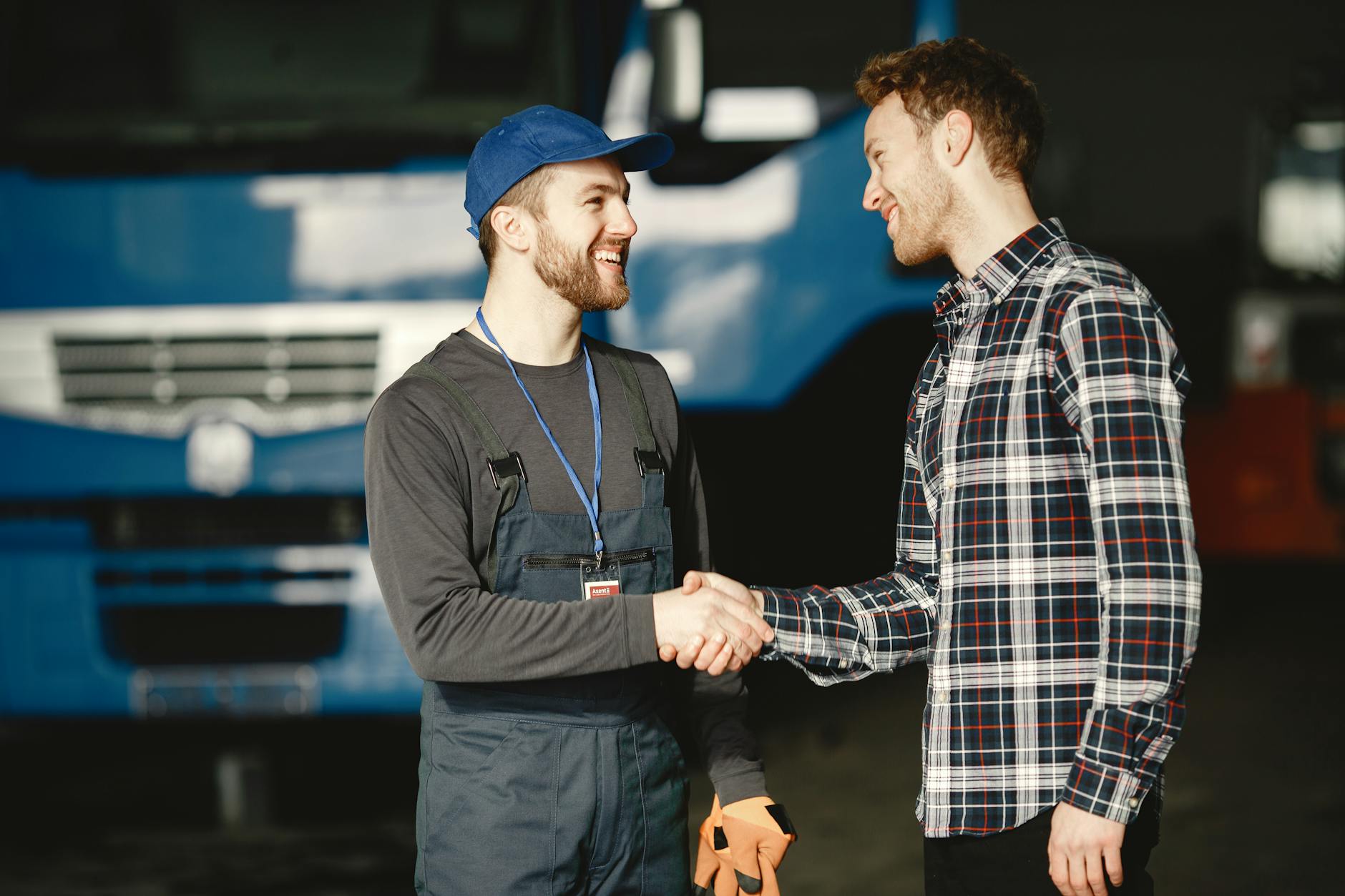 man in blue cap and man in plaid shirt shaking hands
